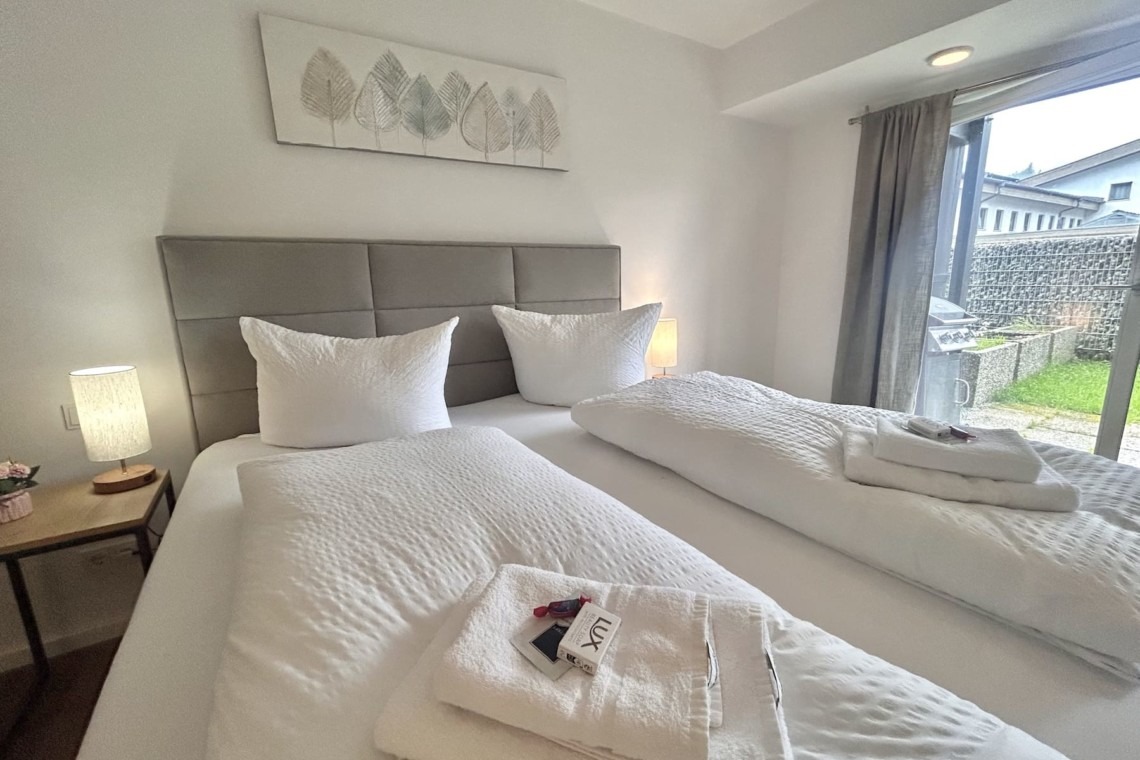 Gemütliches Schlafzimmer in einer modernen Ferienwohnung mit zwei Einzelbetten und künstlerischem Wanddekor, ideal für entspannte Urlaubstage.
