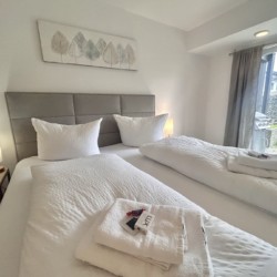 Gemütliches Schlafzimmer in einer modernen Ferienwohnung mit zwei Einzelbetten und künstlerischem Wanddekor, ideal für entspannte Urlaubstage.