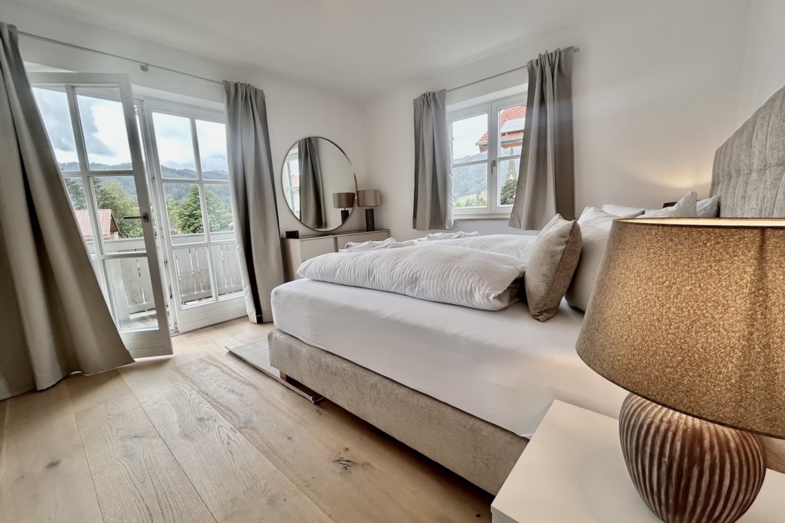 Gemütliches Schlafzimmer in Ferienwohnung mit Bergblick, heller Einrichtung und Balkonzugang.