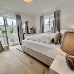 Gemütliches Schlafzimmer in Ferienwohnung mit Bergblick, heller Einrichtung und Balkonzugang.