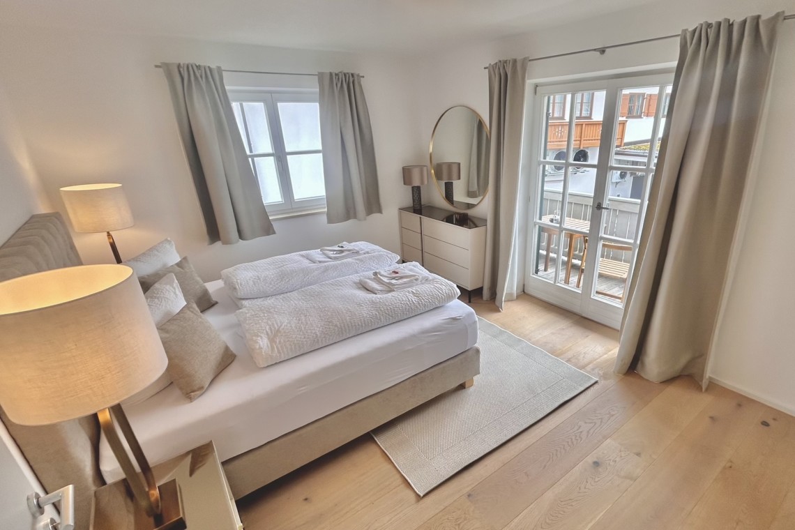 Gemütliches Schlafzimmer in Ferienwohnung mit Doppelbett, modernem Interieur und viel Licht. Ideal für Urlaub und Entspannung.