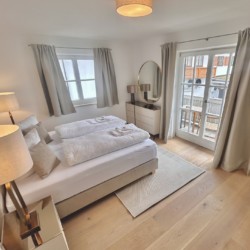 Gemütliches Schlafzimmer in Ferienwohnung mit Doppelbett, modernem Interieur und viel Licht. Ideal für Urlaub und Entspannung.