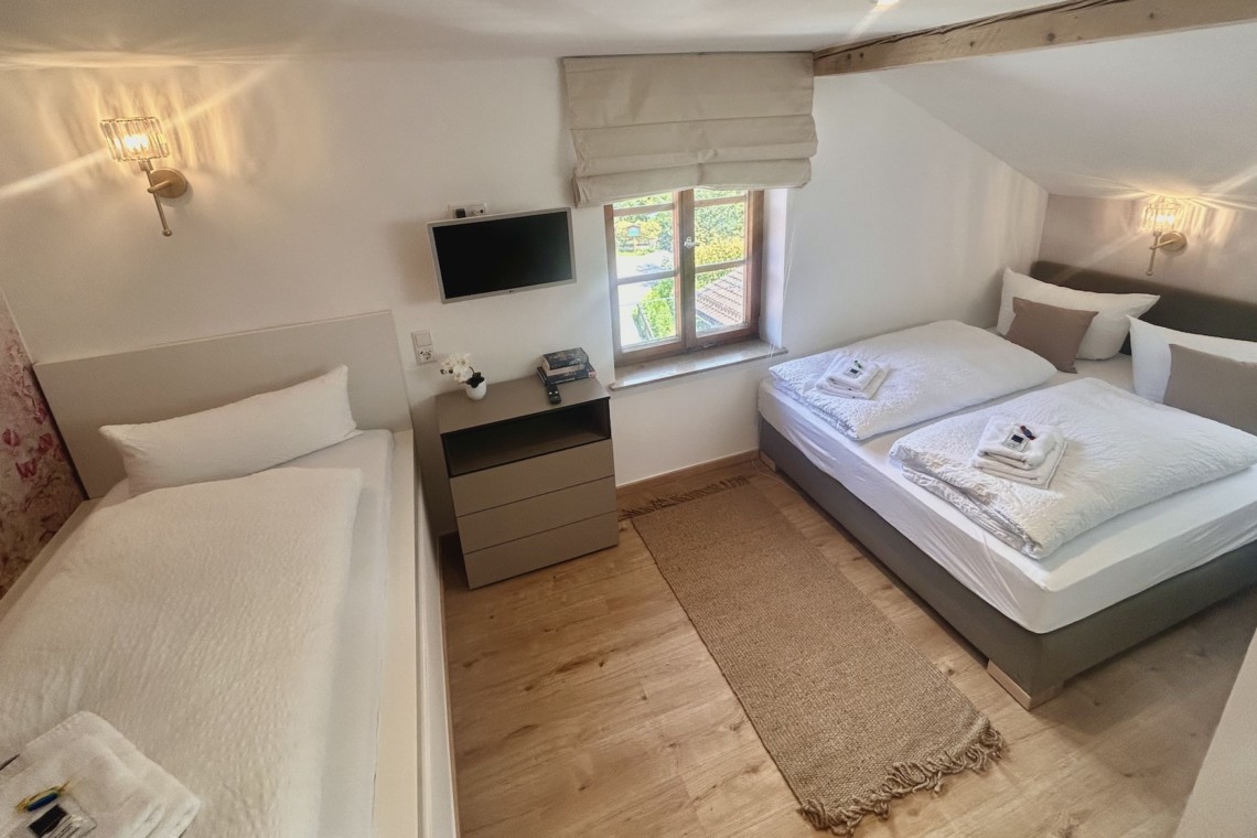 Gemütliche Ferienwohnung mit Doppel- & Einzelbett, TV und warmem Holzboden. Ideal für einen entspannten Urlaub.