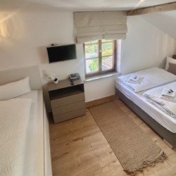 Gemütliche Ferienwohnung mit Doppel- & Einzelbett, TV und warmem Holzboden. Ideal für einen entspannten Urlaub.