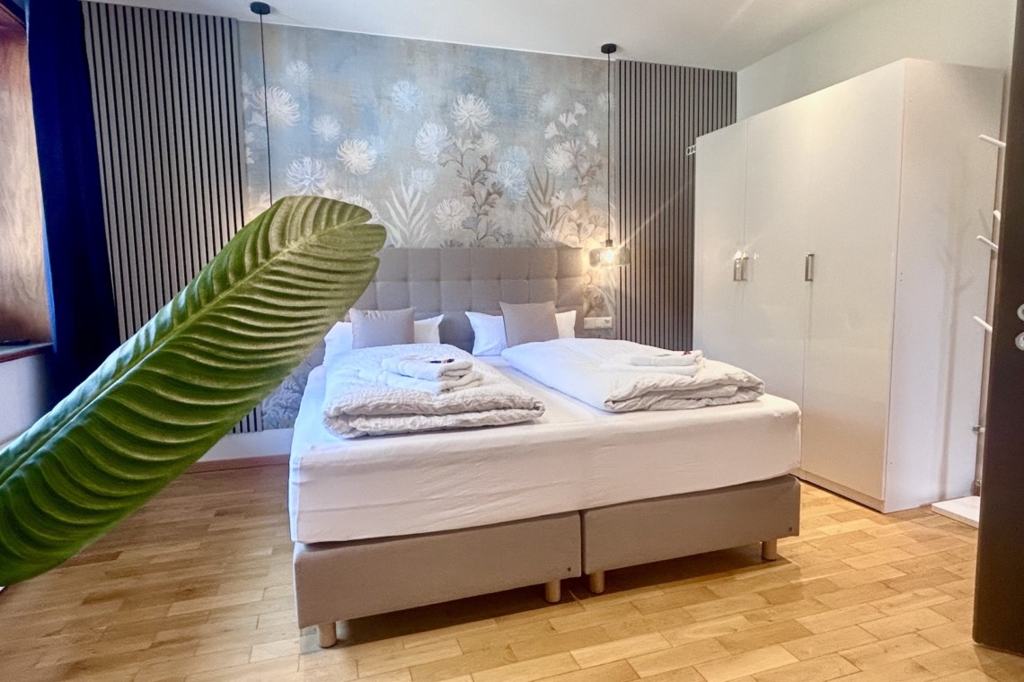 Gemütliches, stilvolles Zimmer in der Ferienwohnung "Die Königslinde" mit komfortablem Bett und eleganter Einrichtung.