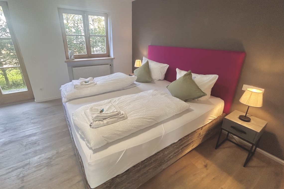 Gemütliches Schlafzimmer in Ferienhaus Seeblick, ideal für entspannten Urlaub, mit Doppelbett, Beistelltisch und Lampen.