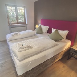 Gemütliches Schlafzimmer in Ferienhaus Seeblick, ideal für entspannten Urlaub, mit Doppelbett, Beistelltisch und Lampen.