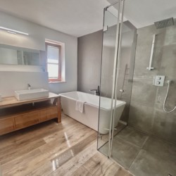 Modernes Bad in Ferienhaus Seeblick, mit Badewanne, Dusche, Doppelwaschbecken; ideal für erholsamen Urlaub.