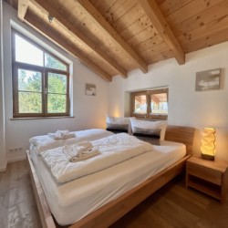 Gemütliches Schlafzimmer in Ferienhaus Seeblick mit Holzbalkendecke und charmantem Dekor, ideal für Erholung.