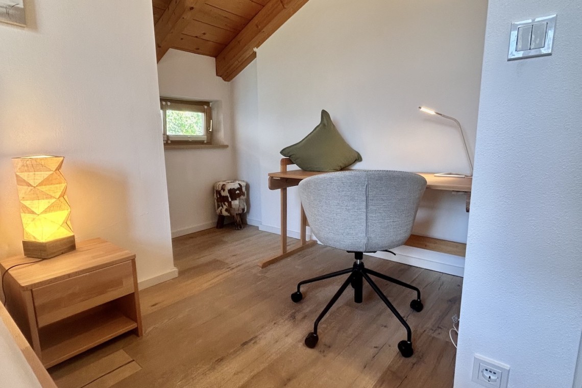 Gemütliches Arbeitszimmer in Ferienhaus mit Holzdecke, hellem Interieur und modernem Schreibtisch – ideal für entspannte Auszeit.